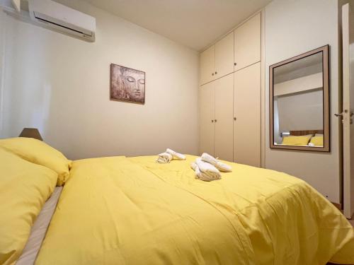 a bedroom with a yellow bed with towels on it at Albert's Apartment Mackenzie 001 in Larnaka
