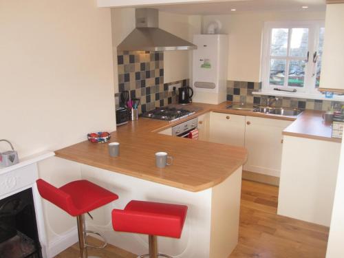 a kitchen with a counter and two red stools at Bosun's Rest in Beer
