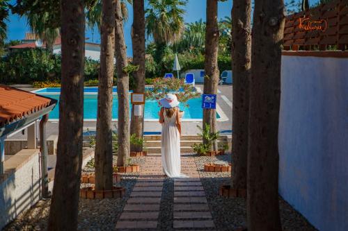 a woman in a white dress standing in front of a pool at Hotel Kalura in Cefalù