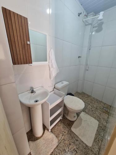a white bathroom with a toilet and a sink at Casa de Maria in Aparecida