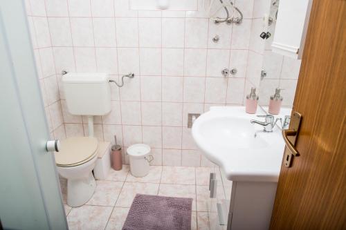 un baño con inodoro y lavabo en apartments VIGI - II, en Povljana
