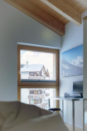 a room with a window and a table and a building at Victoria's Home - luxurious penthouse in Saas-Fee