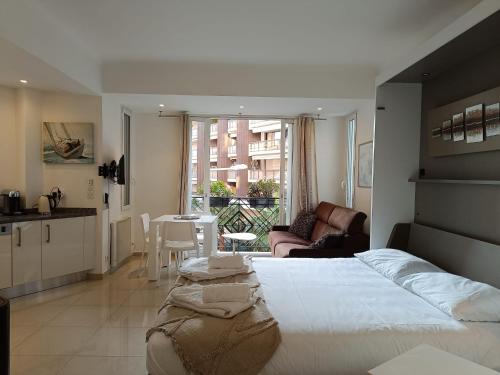 une chambre avec un grand lit blanc et une cuisine dans l'établissement Elegant studio a 50m de la Croisette et ses plages - Ada Serenity Beach, à Cannes