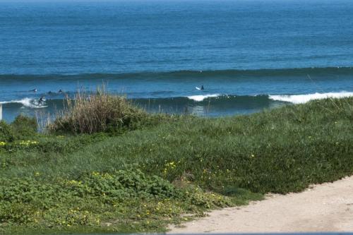 a group of surfers riding the waves in the ocean at Vivenda Sol E Mar in Baleal