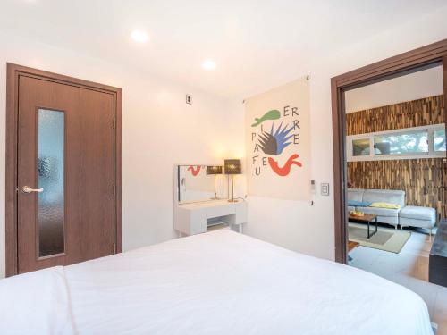 a bedroom with a white bed and a door at Jeju Love Stay Yellow in Jeju