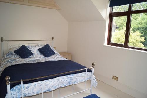 a bedroom with a bed with blue sheets and a window at 2 Buckatree Cottage in Wellington