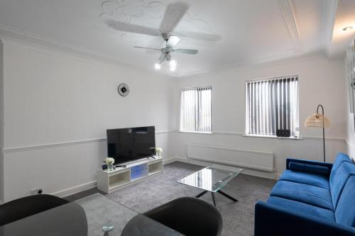 a living room with a blue couch and a tv at 2-bedroom- Stoke-on-Trent-Sleeps 5-PetsOk in Stoke on Trent