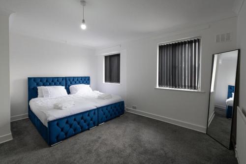a blue bed in a white room with a mirror at 2-bedroom- Stoke-on-Trent-Sleeps 5-PetsOk in Stoke on Trent