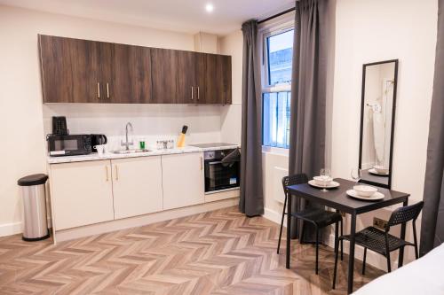 ロンドンにあるPillo Rooms Apartments - Chelseaの白いキャビネットとテーブルと椅子のあるキッチン