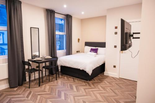 ロンドンにあるPillo Rooms Apartments - Chelseaのベッドとテーブルとテレビのある寝室