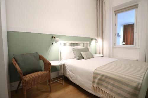 a bedroom with a bed and a chair and a window at Giraffe House in Lisbon