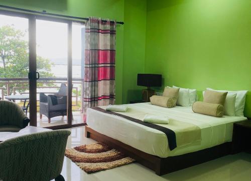 a bedroom with a large bed with green walls at Blue Harbour Inn in Trincomalee