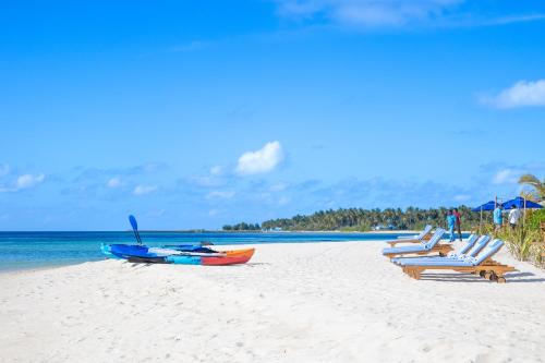 a group of lounge chairs and a boat on a beach at The MAVERICK SURF AND DIVE BOUTIQUE HOTEL - Book 10 Nights and get 1 Free Night - Free Speed Boat Service - Kids Stay Free in Laamu