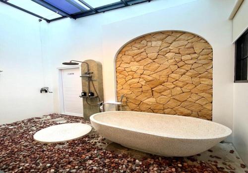 a bathroom with a large tub and a stone wall at Sampai Villa Teras Breksi in Randugunting