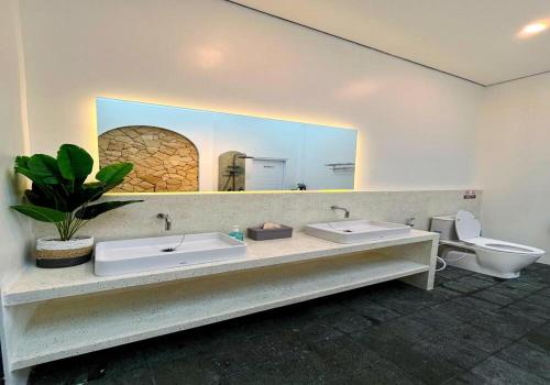 a bathroom with two sinks and a mirror and a toilet at Sampai Villa Teras Breksi in Randugunting