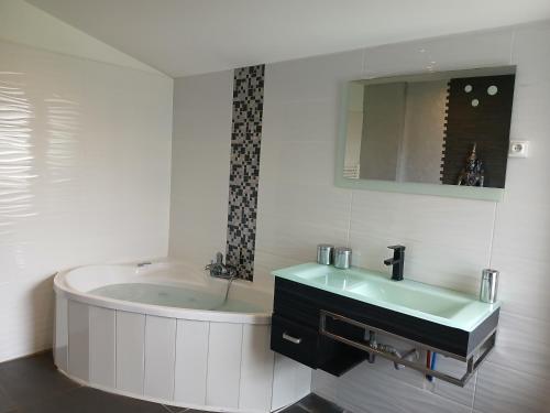 une salle de bain blanche avec une baignoire et un lavabo dans l'établissement maison à la campagne prés de la ville, à Aiglemont