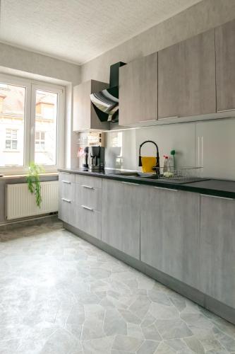 a kitchen with gray cabinets and a tile floor at Ruhige Wohnung auf dem Sonnenstein in Pirna