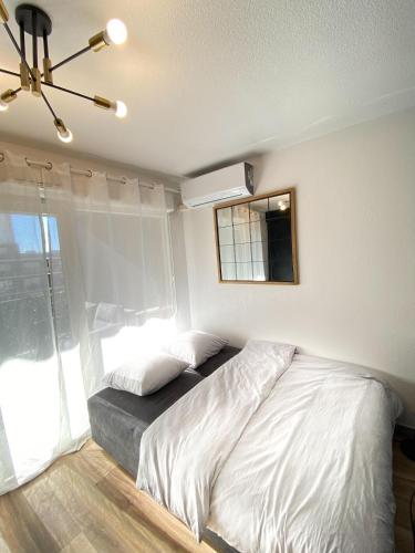 une chambre avec un lit blanc et une fenêtre dans l'établissement Le Mayda - Parking Privé Gratuit, à Marseille