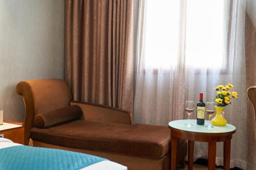 a hotel room with a chair and a table with wine glasses at Kaiserdom Hotel Baiyun Airport-24-hour Airport-Free shuttle bus in Huadu