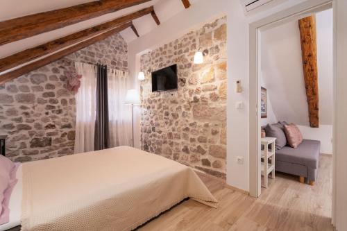 ein Schlafzimmer mit einem Bett und einer Steinwand in der Unterkunft ZUZORI apartments in Dubrovnik