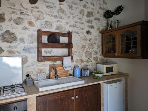 a kitchen with a sink and a stone wall at Passo del Mattino in Locati