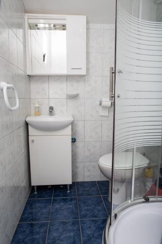a white bathroom with a sink and a toilet at apartments VIGI - III in Povljana