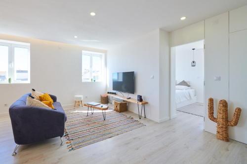 a white living room with a couch and a tv at Apartment with Beach View - Ala-Arriba in Póvoa de Varzim