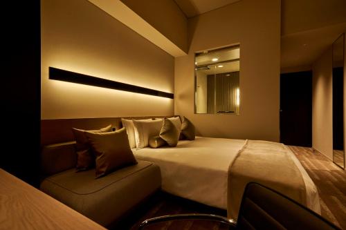 a bedroom with a bed and a chair and a mirror at The Royal Park Hotel Iconic Tokyo Shiodome in Tokyo