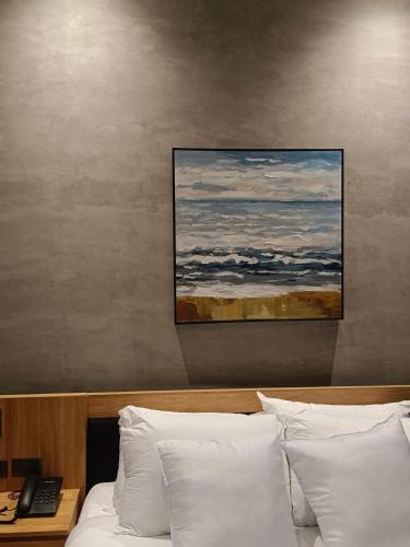 a painting hangs above a bed with white pillows at Caldwell Boutique Hotel in Legazpi