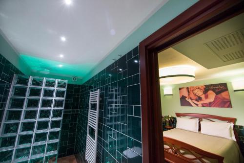 a bathroom with a green tiled shower with a bed at B&B 7 Vizi in Colà di Lazise