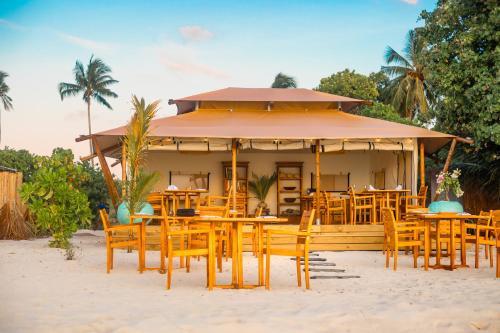 a restaurant with wooden tables and chairs on the beach at The MAVERICK SURF AND DIVE BOUTIQUE HOTEL - Book 10 Nights and get 1 Free Night - Free Speed Boat Service - Kids Stay Free in Laamu