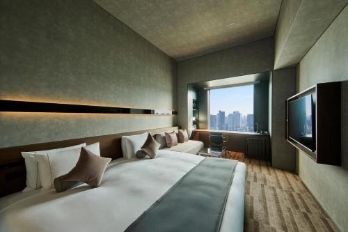 a hotel room with a large bed and a television at The Royal Park Hotel Iconic Tokyo Shiodome in Tokyo