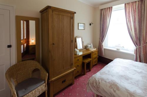 um quarto com uma cama, uma cómoda e um espelho em Abacourt House em Keswick