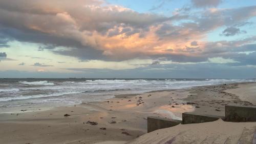 a beach with a cloudy sky and the ocean at Belle résidence in Hammam Sousse