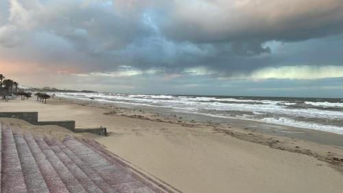 a beach with a cloudy sky and the ocean at Belle résidence in Hammam Sousse