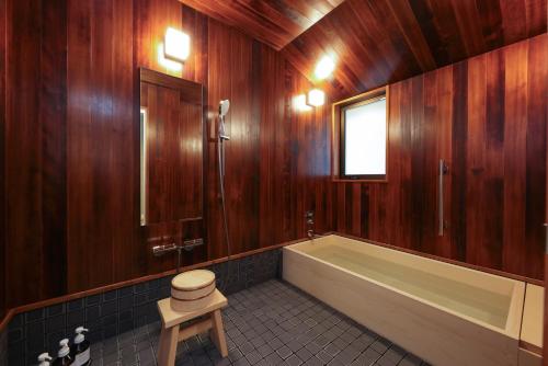 a bathroom with wooden walls and a tub and a stool at Tsukihitei in Nara