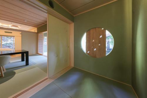 a room with a circular window in a green wall at Tsukihitei in Nara