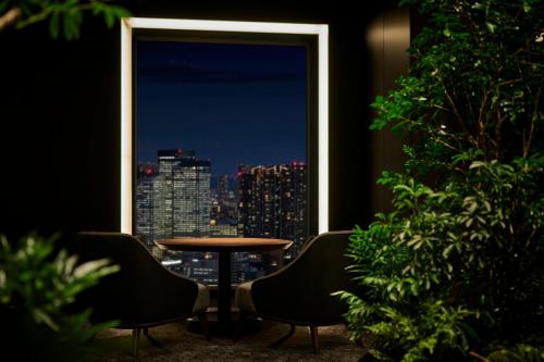 a table and chairs in a room with a window at The Royal Park Hotel Iconic Tokyo Shiodome in Tokyo