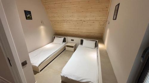 two beds in a small room with wooden ceilings at AFORREST Family Resort in Qusar