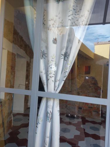 a window with white curtains in a room at Su Furriadroxiu in San Vito