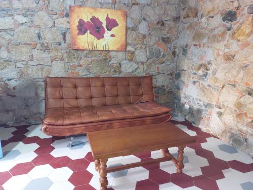 a brown leather couch sitting in front of a stone wall at Su Furriadroxiu in San Vito