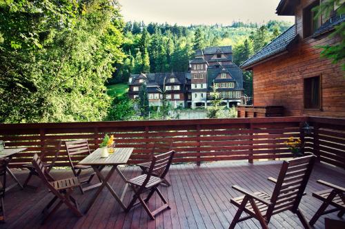 a deck with tables and chairs and a house at Górska Legenda Apartamenty & Domki in Szczyrk