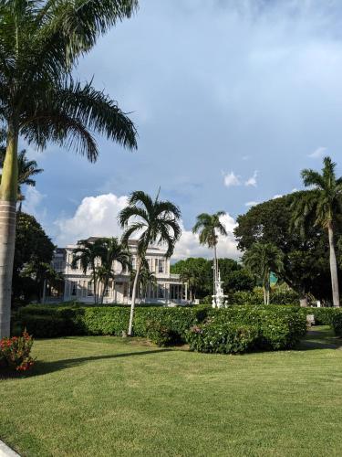 a white house with palm trees in a park at BridgeView Arcadia One in Portmore