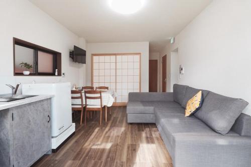 a living room with a couch and a kitchen at Namba shiokusa in Osaka
