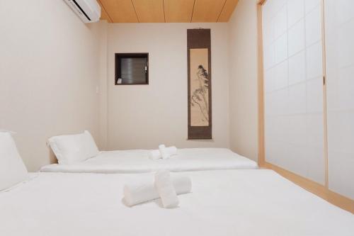 two beds in a white room with towels on them at Namba shiokusa in Osaka