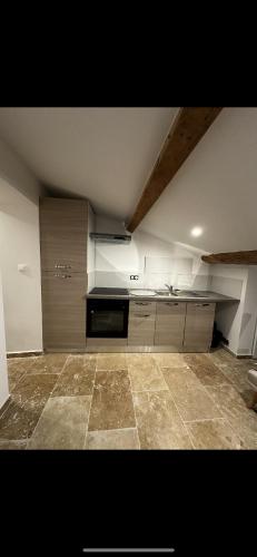 une cuisine avec des armoires blanches et un sol carrelé dans l'établissement Studio sous pente, à Lambesc