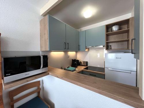 - une cuisine avec des placards bleus et un four micro-ondes dans l'établissement Maison cosy proche plage avec jardinet et parking privé - 6 couchages, 2 chambres - FR-1-224-43, à Saint-Gilles-Croix-de-Vie