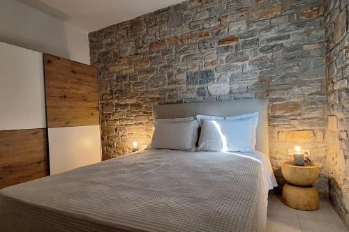a bedroom with a large bed with a stone wall at Akallis Villa in Galini