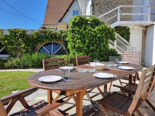 une table en bois avec des assiettes et des verres dans l'établissement Maison Familiale, Plage à 250m, Calme, Jardin, Terrasse, WIFI - FR-1-465-75, à Merville-Franceville-Plage