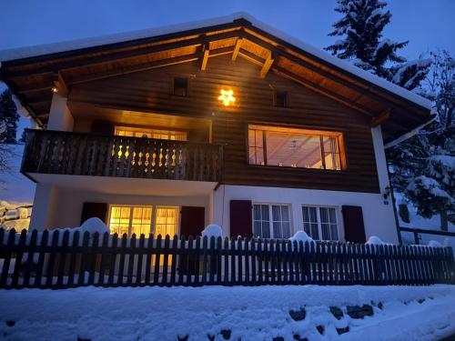 a house with a fence in the snow at Chalet Im Wieselti in Langwies